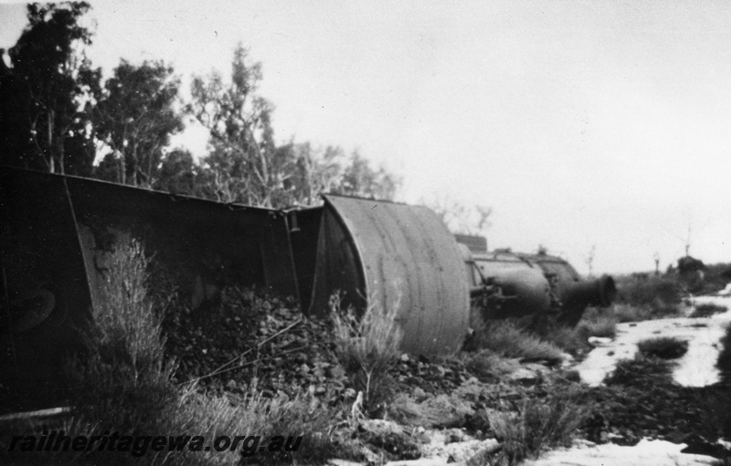 P14703
3 of 3, FS class 427 steam locomotive derailed near Muja on the Muja-Centaur-Collie line, BN line,  view of loco on its side with coal spilled out of the tender.  Date of derailment 23/8/1955
