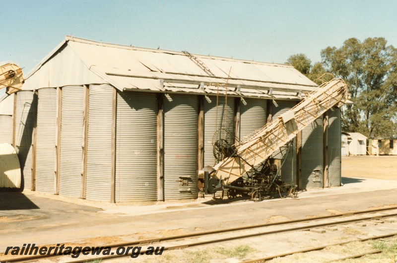 P14718
Corrugated iron grain silo and grain elevator with weighbridge in the background, Burges Siding, GSR line.
