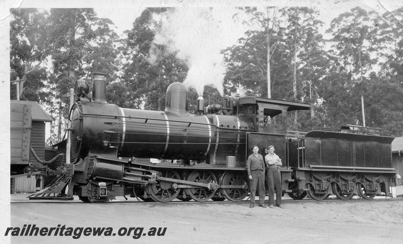 P14859
Bunnings YX class 86 steam locomotive, side view, with two men posing for the photograph next to the loco, Donnelly River Mill.
