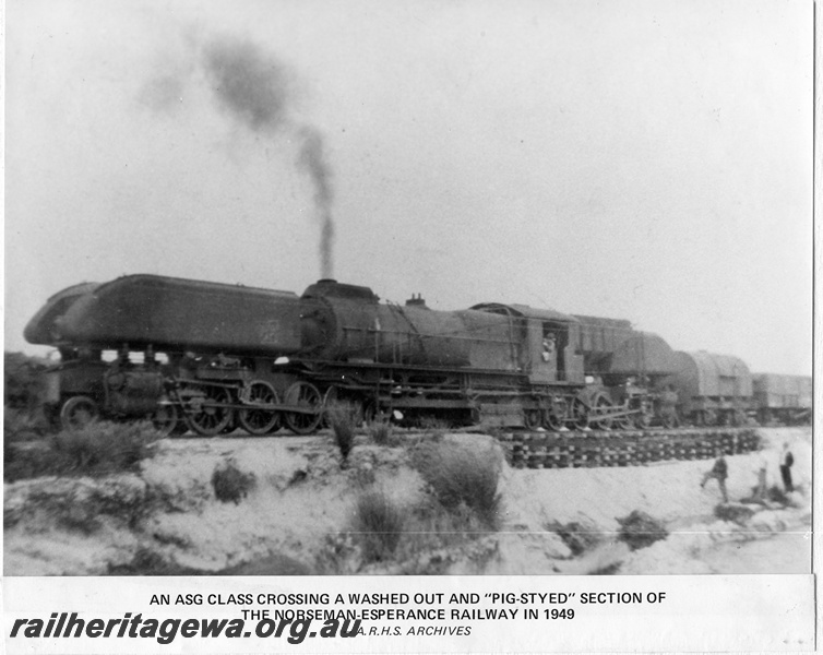 P14879
ASG class Garratt articulated steam locomotive goods train crossing pig-styed section of a wash out, towing a water tanker, front and side view, CE line.
