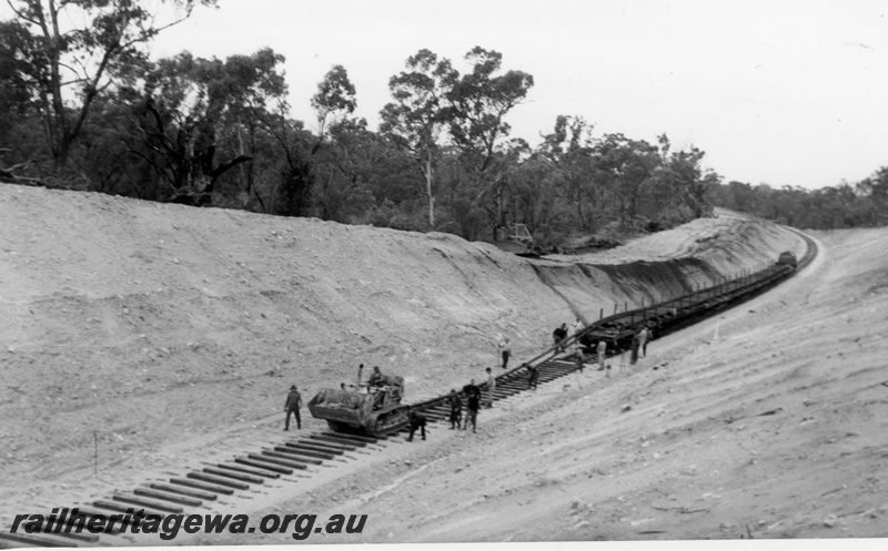 P14982
Track laying on bauxite line. Bulldozer pulling rails off flat wagons. KJ line, Same as P14973 & P14974.
