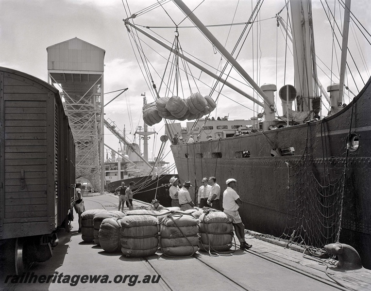 P15044
Goods van being unloaded, wool bales on dock and being transferred to ship by crane, workers, 8 Berth, Fremantle Port
