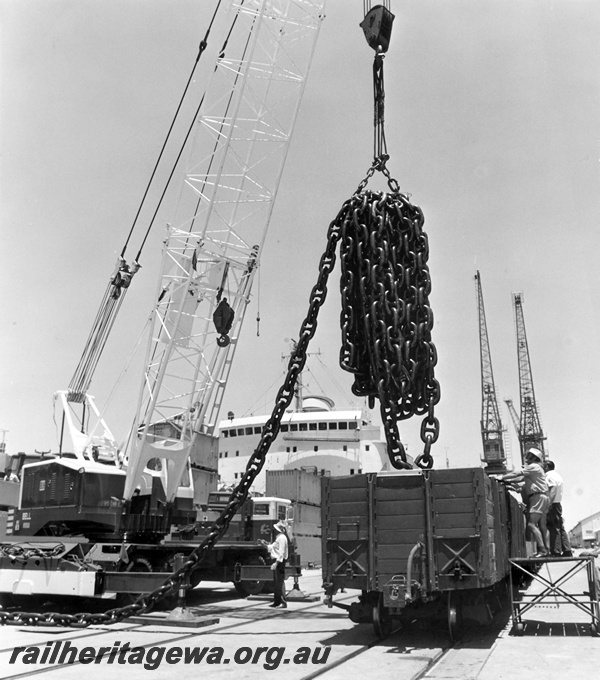 P15061
RCA class wagon, being loaded with chain by Bell 83 mobile crane, overseer, ship and cranes in background, Fremantle Port, see P0296, c1974, (ref: 