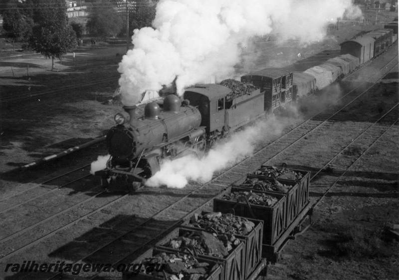 P15124
An unidentified C class steam locomotive departing Katanning for Ongerup. Overhead view of loco, tender and train with M class coal box wagons in foreground. GSR line
