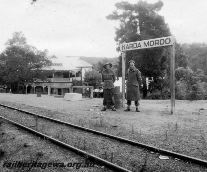 P15146
Karda Mordo station nameboard with servicemen standing next to the sign. MW line. Mundaring Weir Hotel in background.
