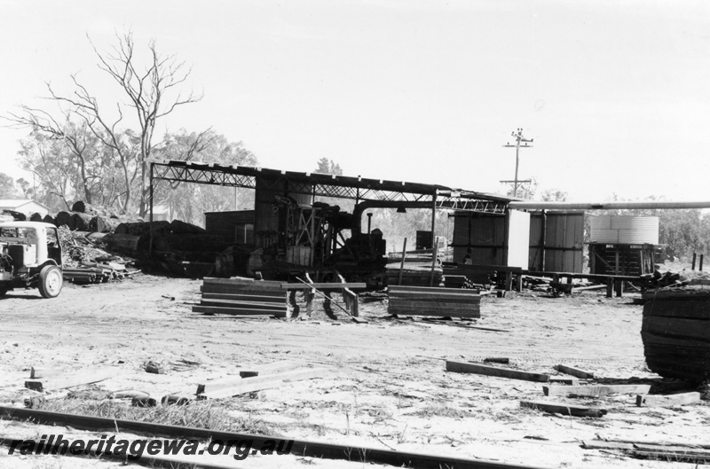 P15173
1 of three views of the sleeper mill located trackside at Narrikup, c1970/71, GSR line, overall view of the mill with rails in the foreground
