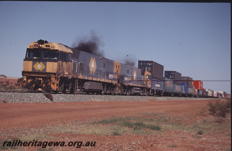 P15211
Pacific National NR class 31 leads a freight train near Parkeston, TAR line, view along the train showing double stack containers
