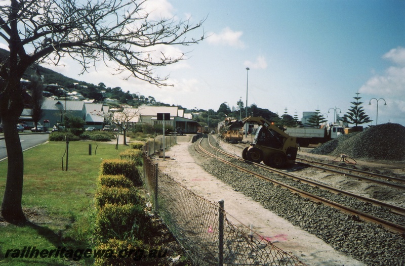 P15371
Albany Yard being modified by John Holland Staff. 'Bobcat' placing metal ballast onto trackage from stockpile to right. Track machine in background and road truck to right. GSR line.
