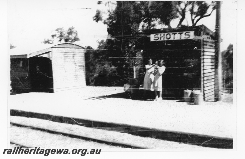 P15745
Station buildings, Shotts, BN line, Passenger Shelter on left and an unidentified structure with women and a baby in front. 
