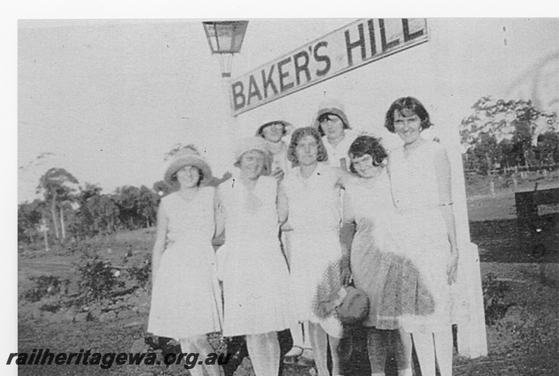 P15810
Station lamp, nameboard, Baker's Hill, ER line, a group of women posing beneath the nameboard, 