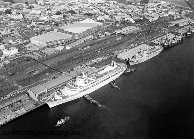 P15842
Turntable, footbridge, signal box, station building, goods shed, Wool Stores, aerial view of Fremantle Yard and harbour, liner 