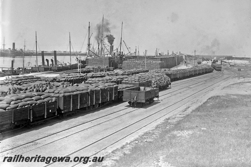 P15856
R class 1668, five plank RA class 5832 and other rakes of open loaded with bagged wheat, empty G class 6599, North Wharf, Fremantle Harbour.

