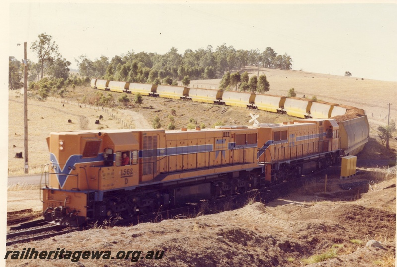 P15886
D class 1562 coupled to another D class diesel loco, both in Westrail orange with blue and white stripe, on wood chip train, rural setting, front and side view 
