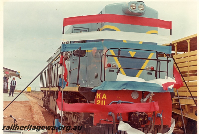 P15922
KA class 211, in light blue with dark blue and yellow stripe livery, breaking through red white and blue ribbons, platform with man standing on it, canopy, side and front view
