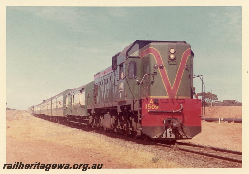 P15933
A class 1509, in green with red and yellow stripe, on tour train of green and cream carriages, rural setting, side and front view
