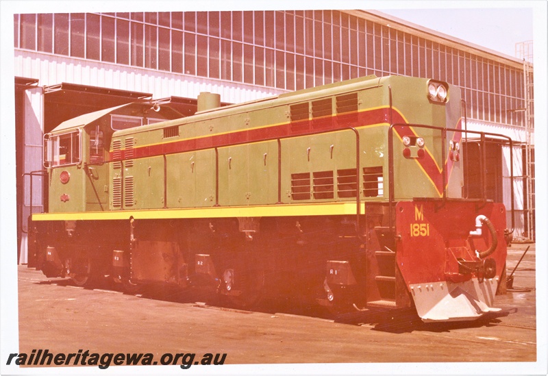 P15945
M class 1851, in green with red and yellow stripe, standing outside shed, side and end view, long end to camera

