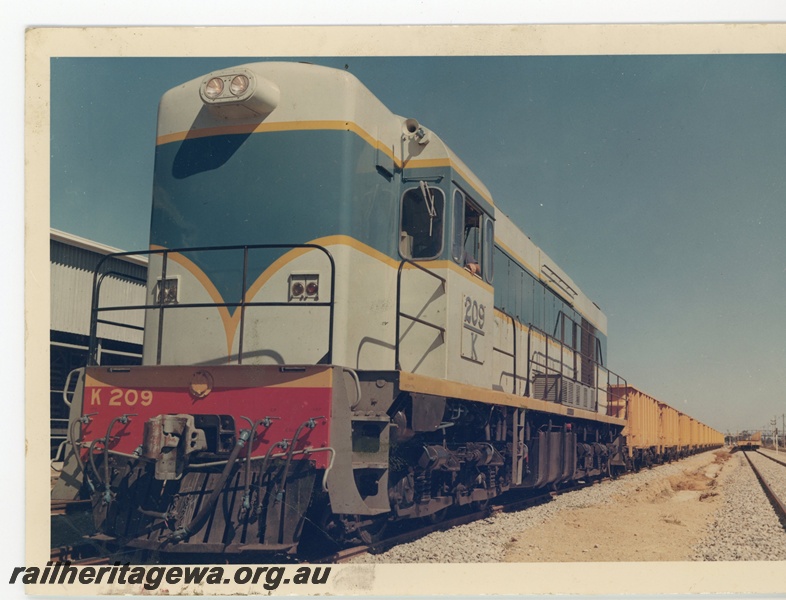 P15958
K class 209, in light blue with dark blue and yellow stripe, on an empty iron ore train at Midland, light signal, front and side view
