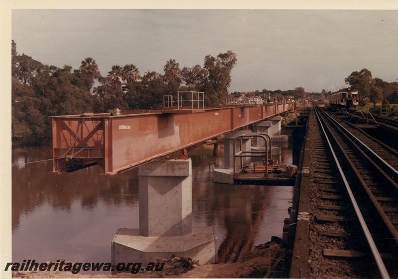 P15990
Concrete and steel bridge, under construction, old bridge being crossed by ADG class railcar set, in red white and green livery, Guildford, ER line
