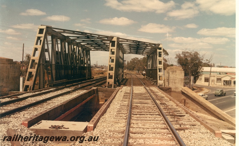 P16010
Mount Lawley Subway, steel girder bridge, in preparation for the laying of standard gauge tracks over bridge, cars emerging from subway, shop advertising 