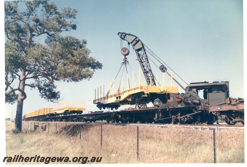 P16026
Cravens 25 ton breakdown crane No. 23, lifting yellow standard WF Class flat wagon, later reclassified to WFDY, off narrow gauge flatbed wagon, WF and WSF wagons on other flat wagons, end and side view from track level
