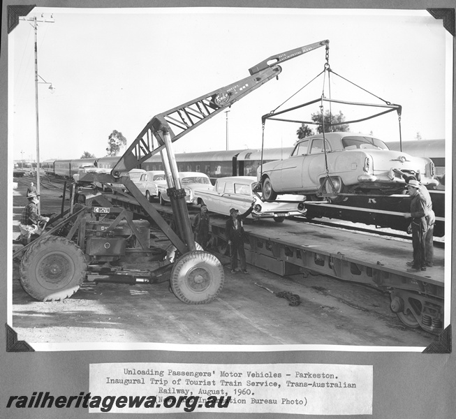 P16185
Commonwealth Railways (CR), passengers motor vehicles being unloaded from flat wagons by International loader C85219, workers, Parkeston, TAR line, inaugural tourist train service
