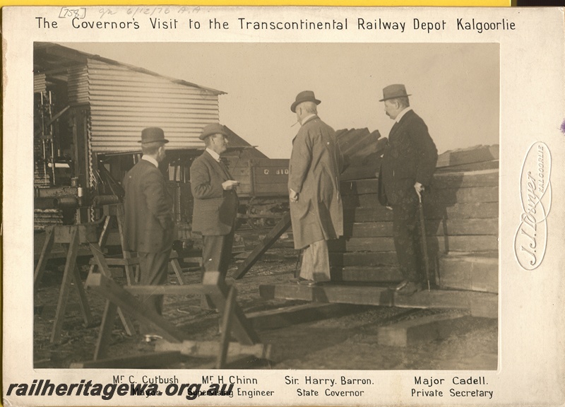P16187
Commonwealth Railways (CR), visit by the WA Governor to Kalgoorlie transcontinental railway depot, pictured from left to right are Mayor C Cutbush, Supervising Engineer H Chinn, Governor Sir Harry Barron, Governor's Private Secretary Major Cadell, standing near water tank and sleepers, Kalgoorlie depot, TAR line, c1915 
