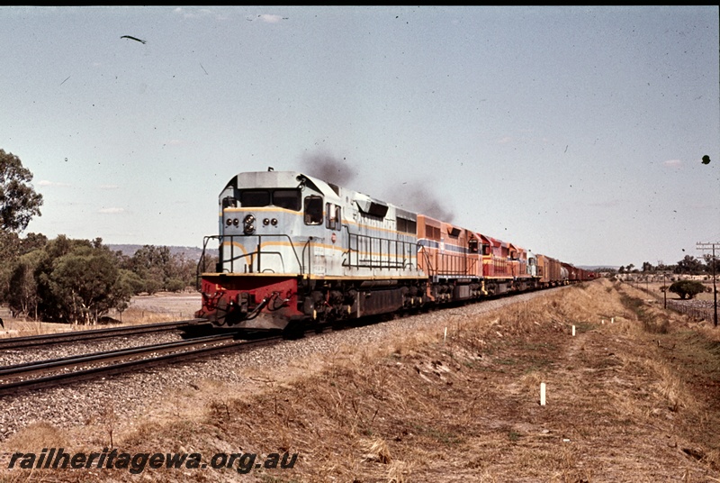 P16669
L class loco, coupled with four other diesel locos, heading a freight train along dual gauge track, rural setting, front and side view
