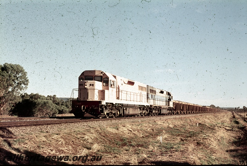 P16677
Two L class locos, one in pink undercoat and the other in light blue with dark blue and yellow stripe, double heading freight train, rural setting, front and side view
