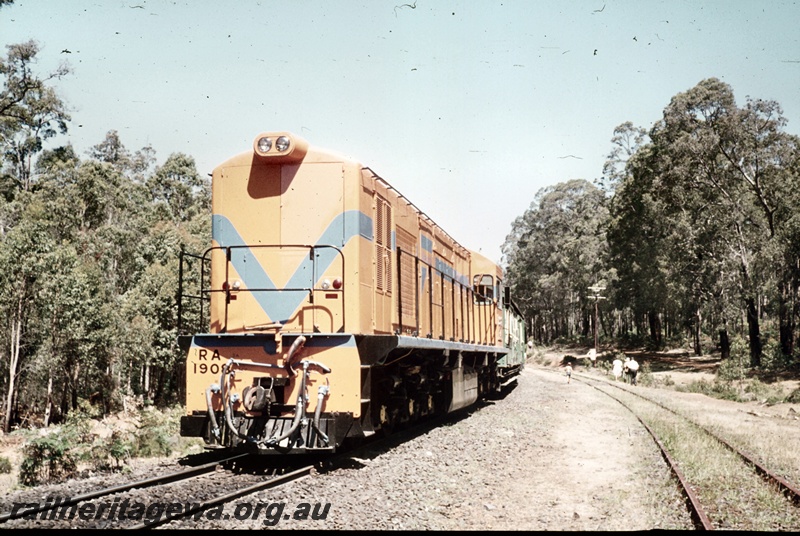 P16680
RA class 1908, in Westrail orange with blue stripe, on excursion train comprising green and cream carriages, passengers on tracks, bush setting, front and side view
