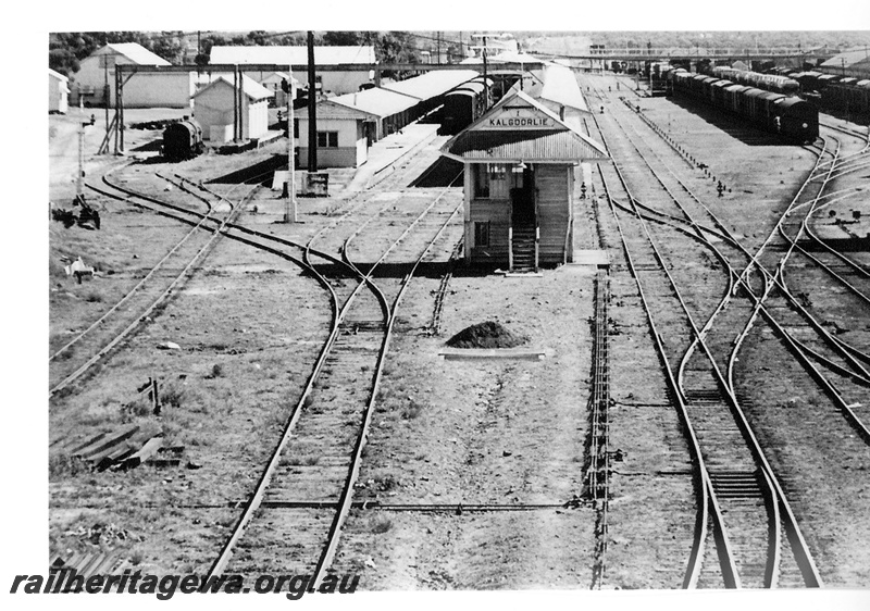 P16695
Overview of Kalgoorlie station and yard, station buildings, canopies, platforms, train standing at platform, signal, signal box, pedestrian footbridge, yard, rakes of wagons, pointwork, Kalgoorlie, EGR line, view from elevated position
