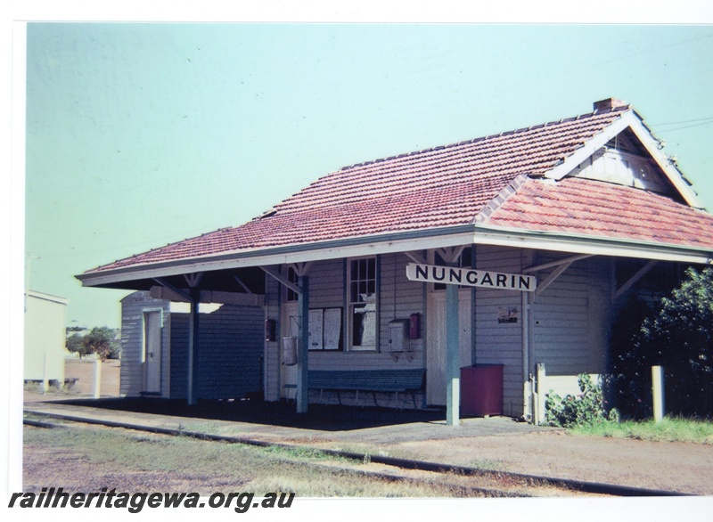 P16702
Station building, weatherboard and tile, other buildings, seat, nearby shrub, Nungarin, GM line 
