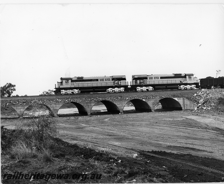 P16738
Cliffs Robe River (CRRIA) M636 class 1713, 1711 haul first train on CRRIA railway crossing Culvert 1. The tree branch in first wagon commemorates first load of ore from new mine.
