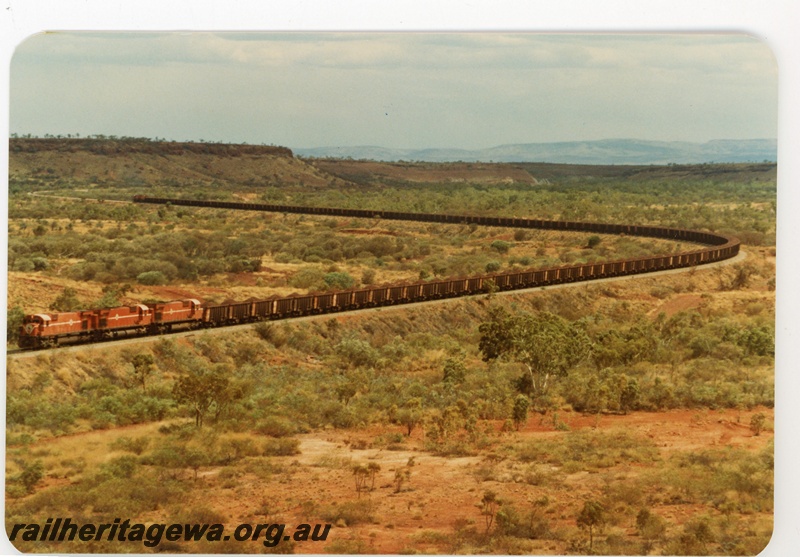 P16747
Mount Newman (MNM) loaded ore train near 227 km. Chichester Range in background.
