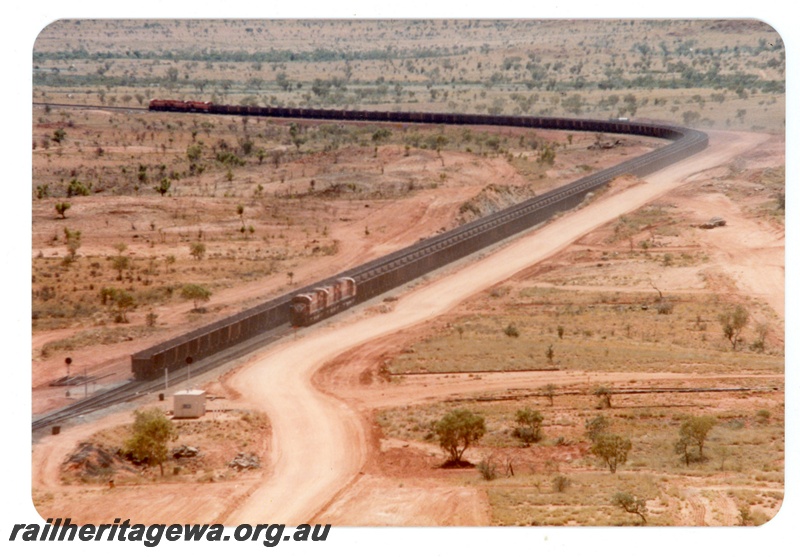 P16754
Mount Newman (MNM) loaded and empty trains cross at Garden loop. Distant view showing the full length of both trains. 
