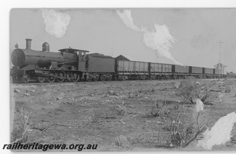 P16798
Commonwealth Railways (CR) G class steam locomotive hauling a construction train east with two TC class wooden water tanks and four TD class water tanks and a R class flat wagon with a mobile workers hut upon it, TAR line. c1916
