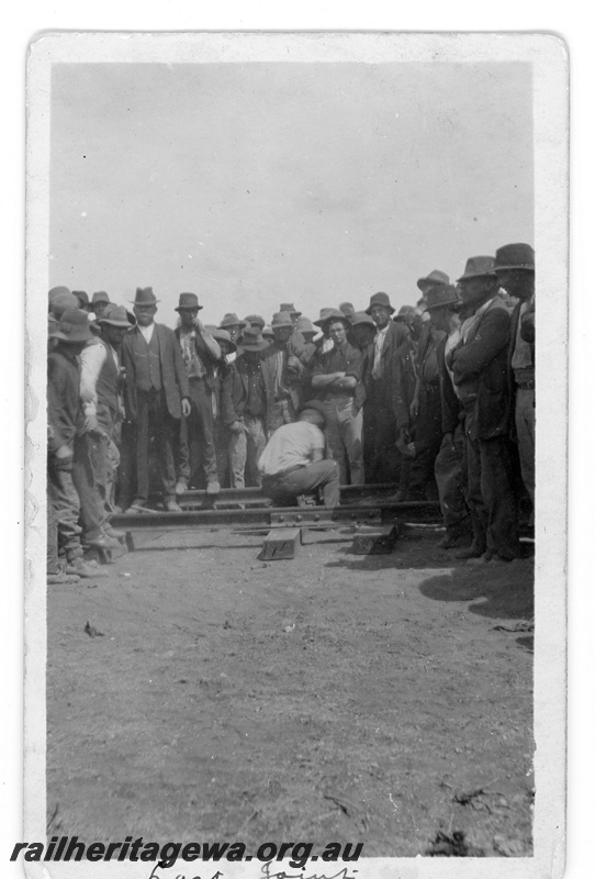 P16812
Commonwealth Railways (CR) - TAR line crowds watch the securing of the last fishplate to connect the railway near Ooldea.
