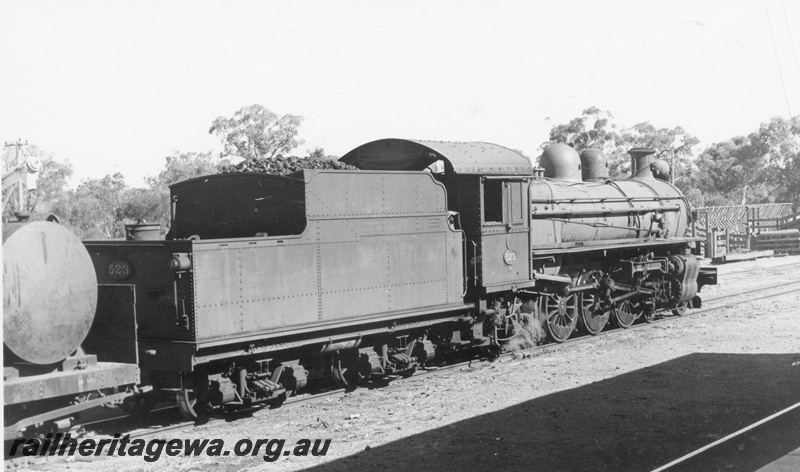 P17033
PR class 523 in the crossing loop, with a goods train between York and Narrogin on the GSR line. Note the frame work of the CBH holding pen in the right background. The JGS class tank on the wagon behind the loco is used for hauling furnace oil.
