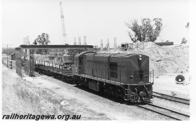 P17134
R class 1901 diesel electric locomotive hauling a short works train at Kwinana. Note the work proceeding on the construction of an overhead road bridge.
