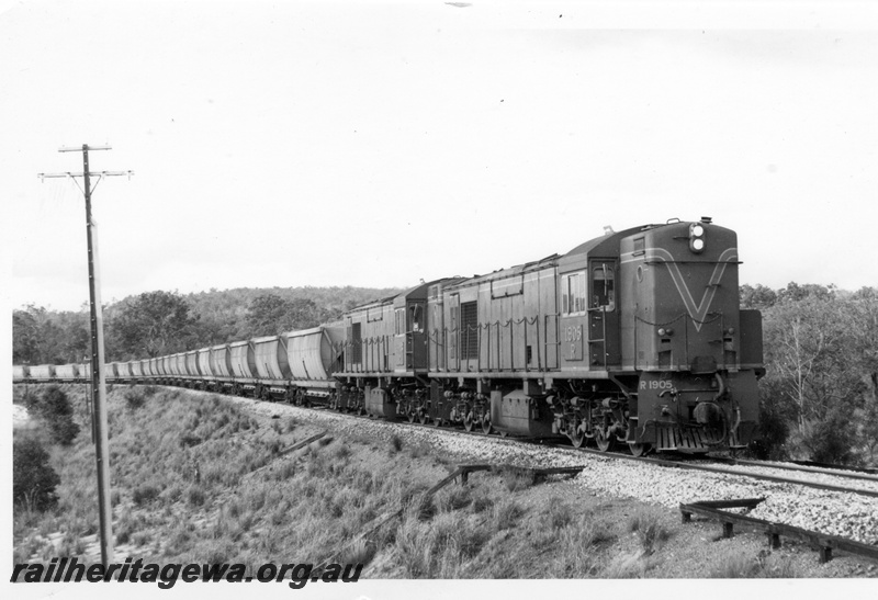 P17135
R class 1905 and R class 1903 diesel electric locomotives hauling a loaded bauxite train of hopper wagons on the Jarrahdale line approaching Mundijong. Note the signalling trunking boxes in the foreground. 
