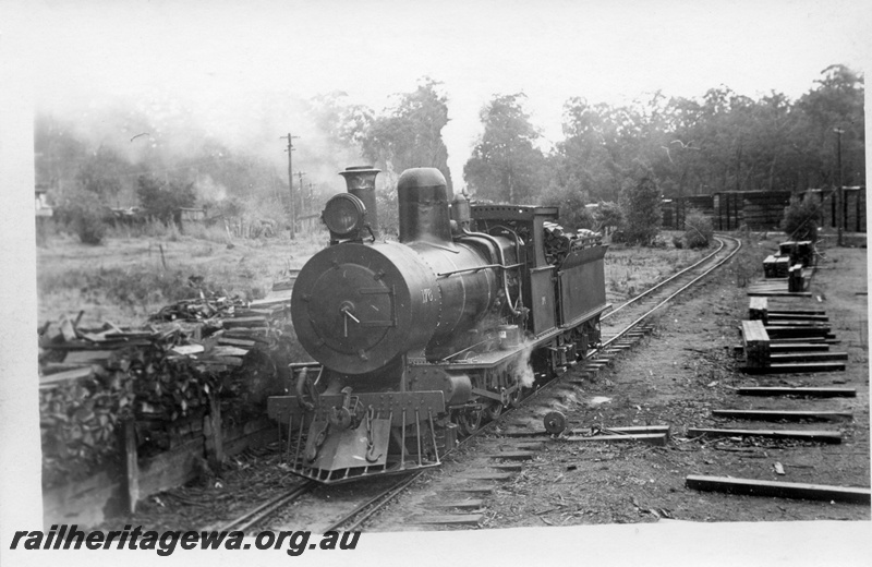 P17139
YX class 176 locomotive at Donnelly Mill yard. Front and side view of loco, cheese knob point lever next to loco and stacks of timber in background.
