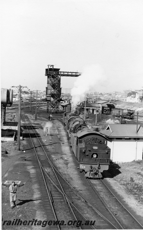 P17146
DM class 586,V class 1211 & PMR class 733 at East Perth loco. Note coal stage at rear, fuel tanks & stand at left with an unidentified building to right. Person at left front appears to be hand signalling the locomotives.
