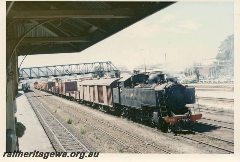 P17166
DM class 588 steam locomotive on goods train, side and front view, passing under the footbridge, front view of diesel railcar at the passenger platform, Midland, ER line.
