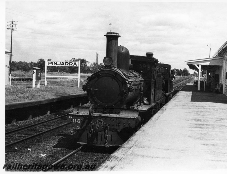 P17256
1 of 4, G class 118 steam locomotive double heading with G class 67 steam locomotive, running light engine, front and side view, nameboard, station building, passenger platform, Pinjarra, SWR line. 
