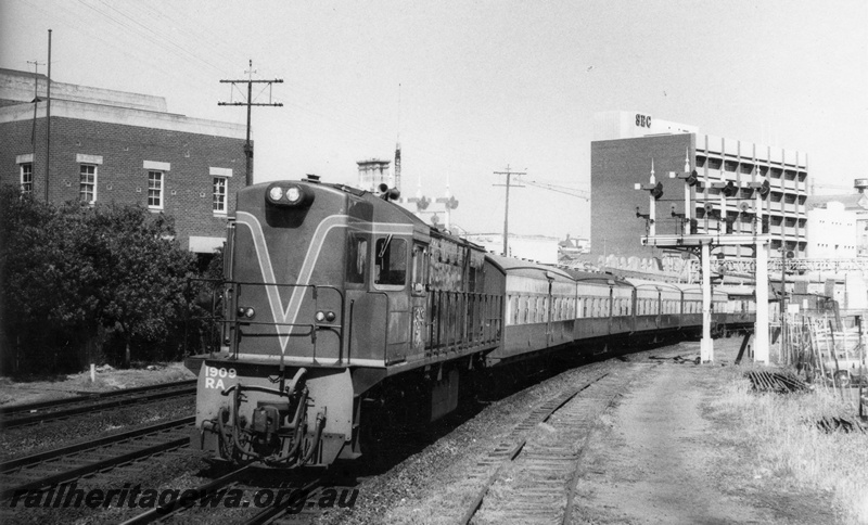 P17294
RA class 1909 diesel locomotive, front and side view, on the Australind, leaving Perth, bracket signals, ER line.
