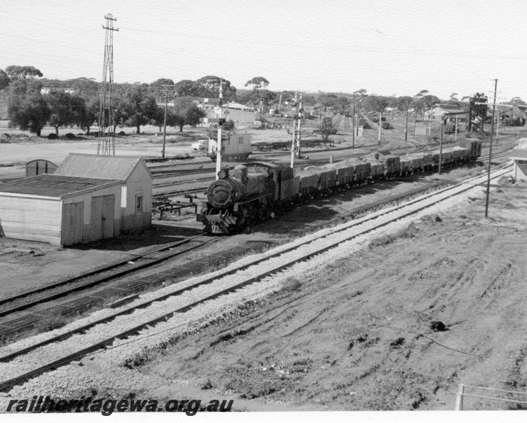 P17302
PM class 701 arriving Merredin from Narembeen. Photo taken from overhead footbridge shows semaphore signals, coal stage in background and yard in left background. Standard gauge track in foreground. 

