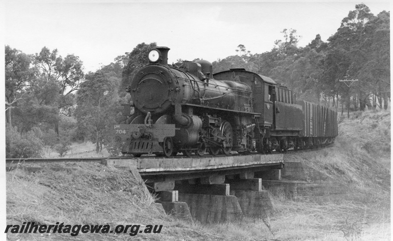 P17330
PM class 704 steam locomotive, front and side view, on a goods train, crossing a bridge, Olive Hill, BN line.
