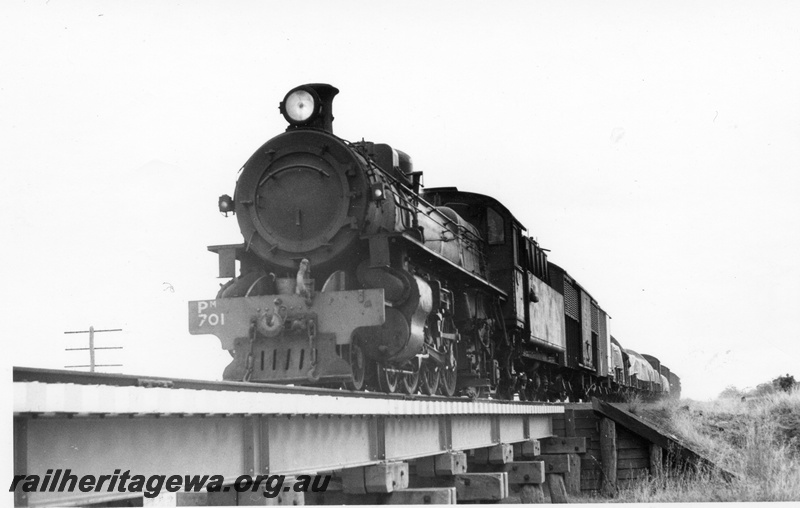 P17359
PM class 701 steam locomotive, on goods train, front and side view, crossing a bridge, BN line.
