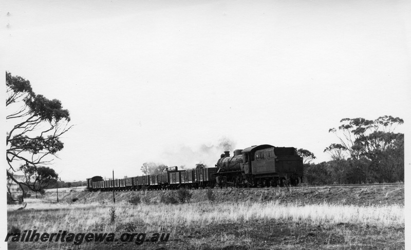 P17399
Steam loco, running tender first, on goods train comprising open trucks and brakevan, moving through rural countryside towards camera, c1969
