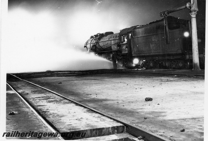 P17477
An unidentified V class steam locomotive outside the Narrogin Loco. GSR line. Note the water column at the rear of the locomotive.
