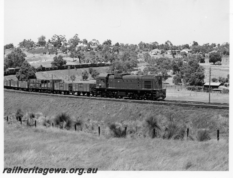 P17608
A class 1510 diesel locomotive hauling an eastbound goods train on the approach to Swan View. ER line. The area in the background is now a housing estate.
